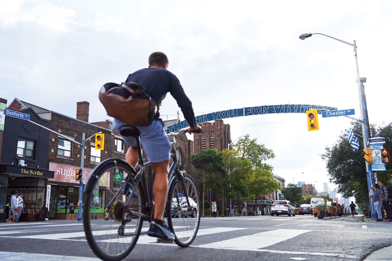 A cyclist riding along Danforth, through Toronto Life's number-one ranked neighbourhood to live in now