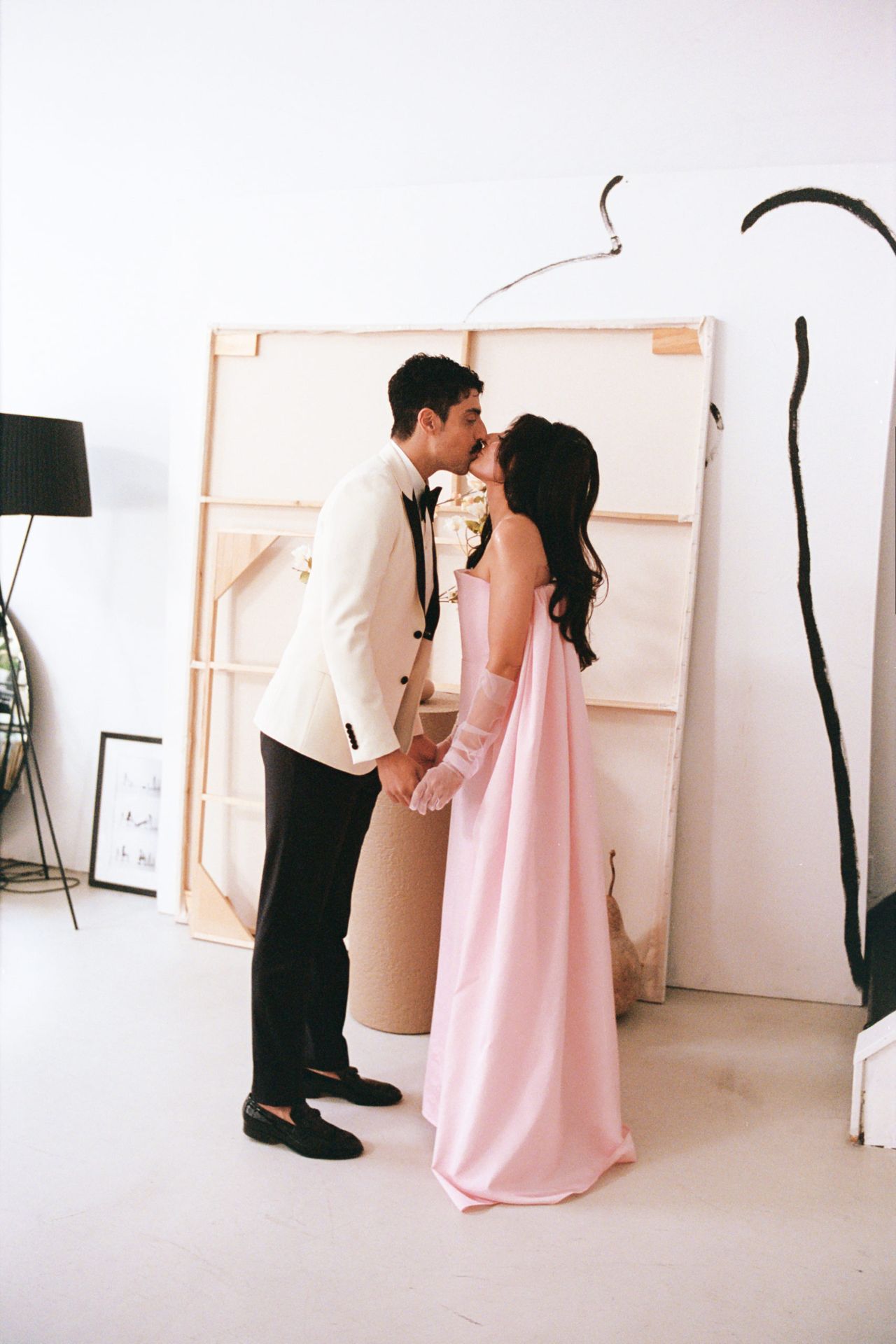 Mani and Roya standing together, kissing, while they get ready