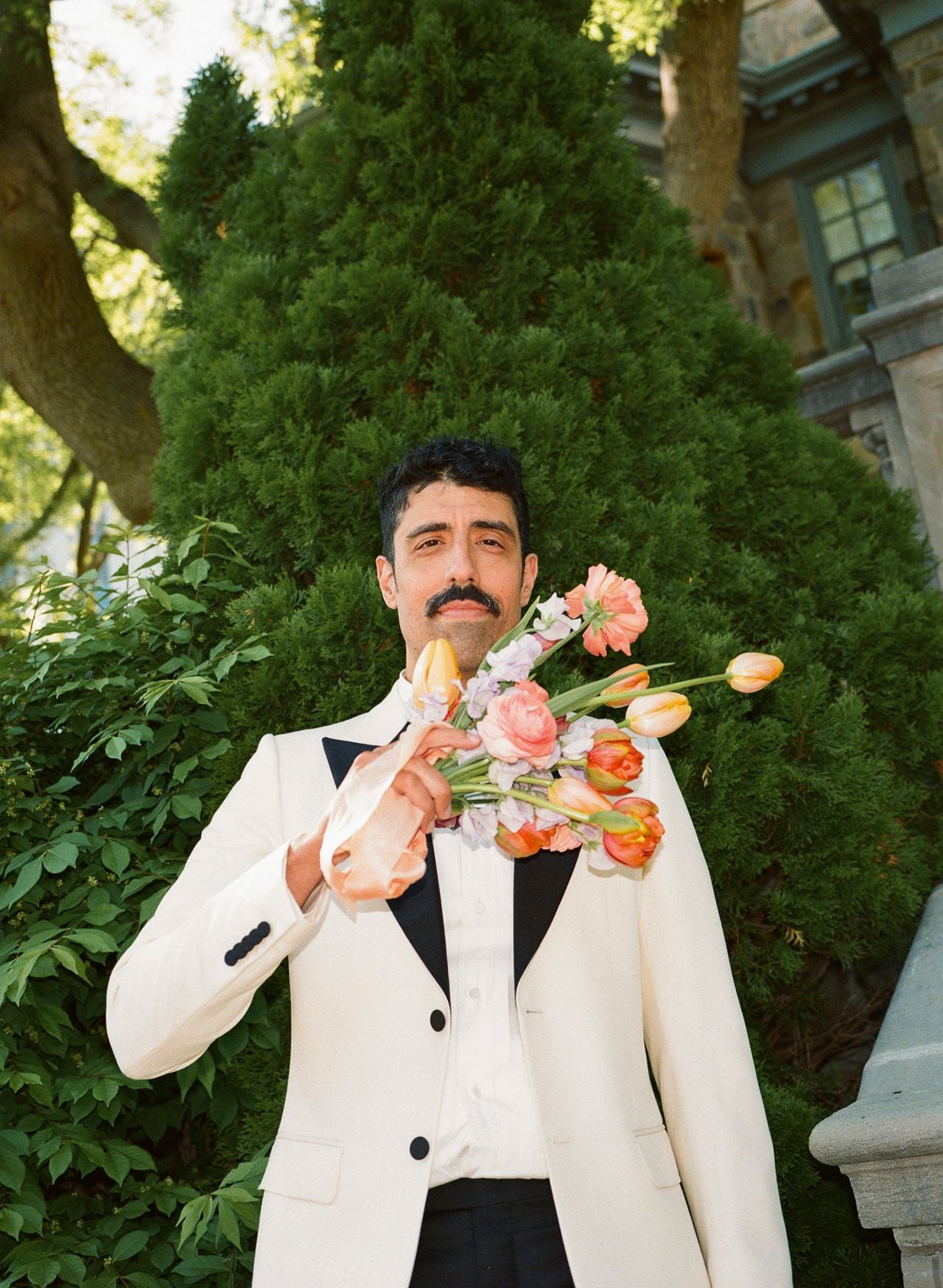 Mani standing, holding a bouquet of flowers