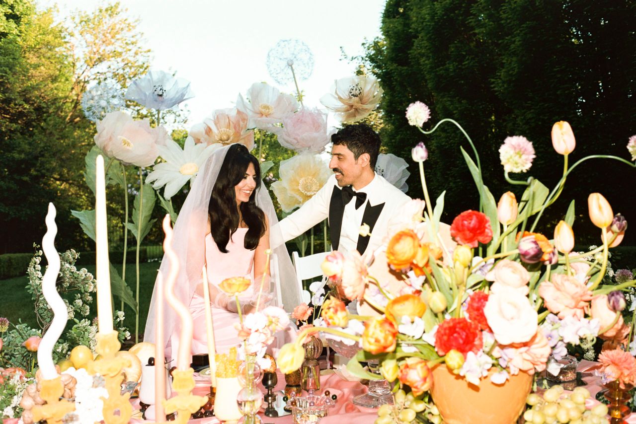 Roya and Mani at the altar on their wedding day, surrounded by colourful decorations