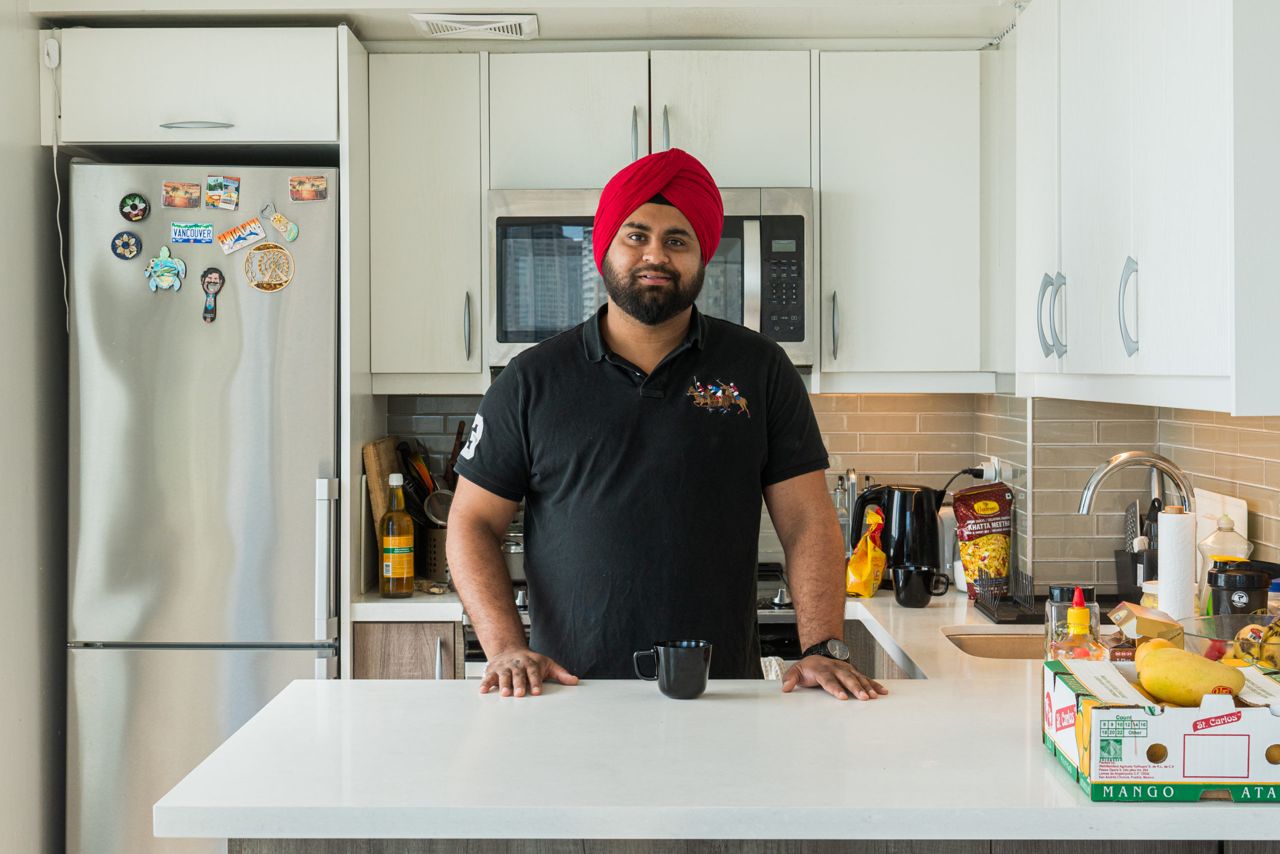 Ravneet standing in his kitchen, wearing a dark coloured polo shirt and a red turban
