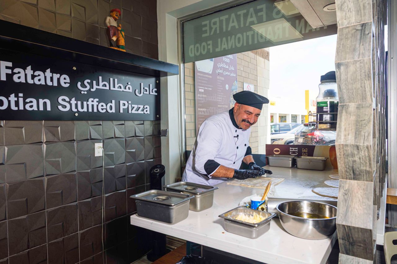 A chef rolls out dough to make feteer, Egyptian stuffed pizza