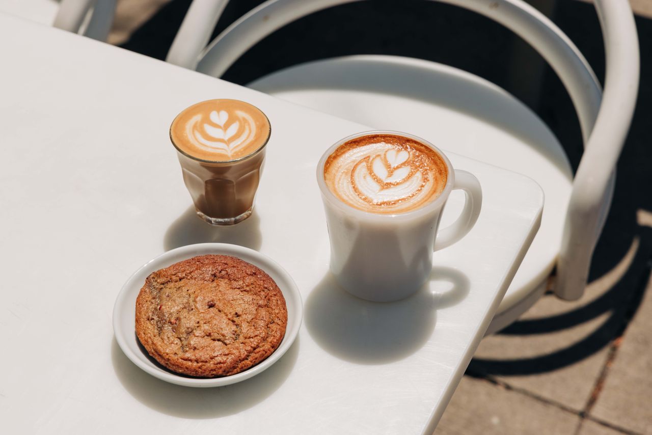 Coffee beverages and a cookie on a patio table