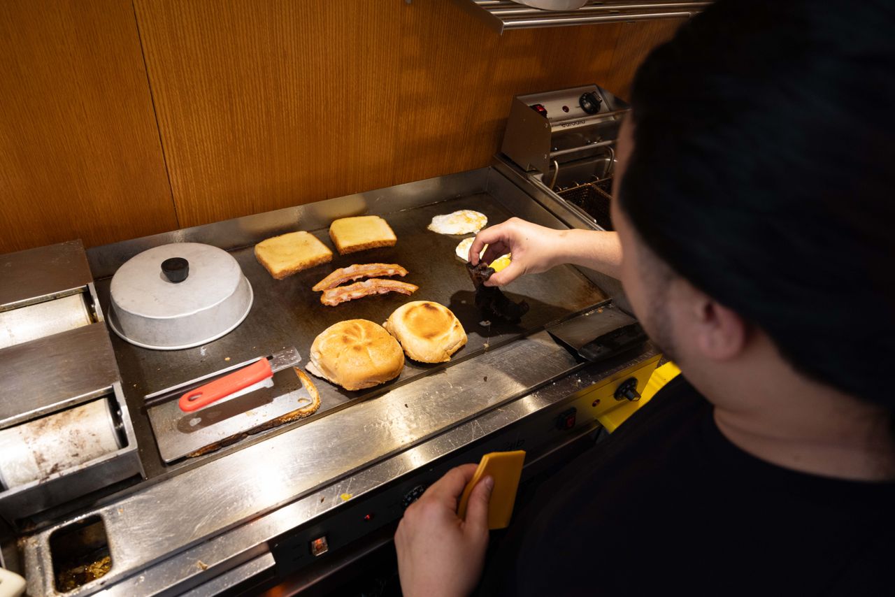 A chef cooks breakfast on a flattop grill at a diner