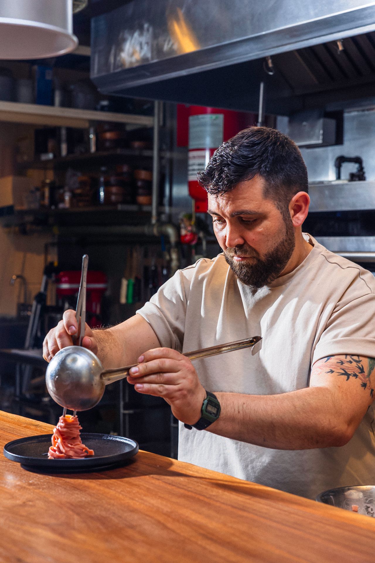 A chef plates pasta in the kitchen at Radici Project