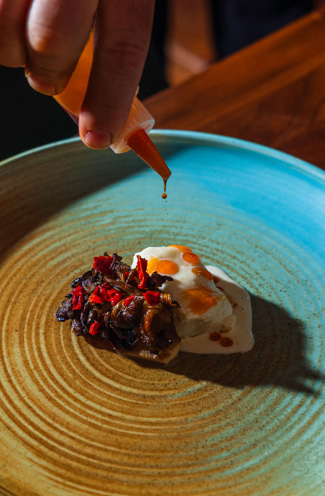 Olive oil–poached halibut served with dashi-braised maitake, finished over binchōtan charcoal and dusted with peperone crusco