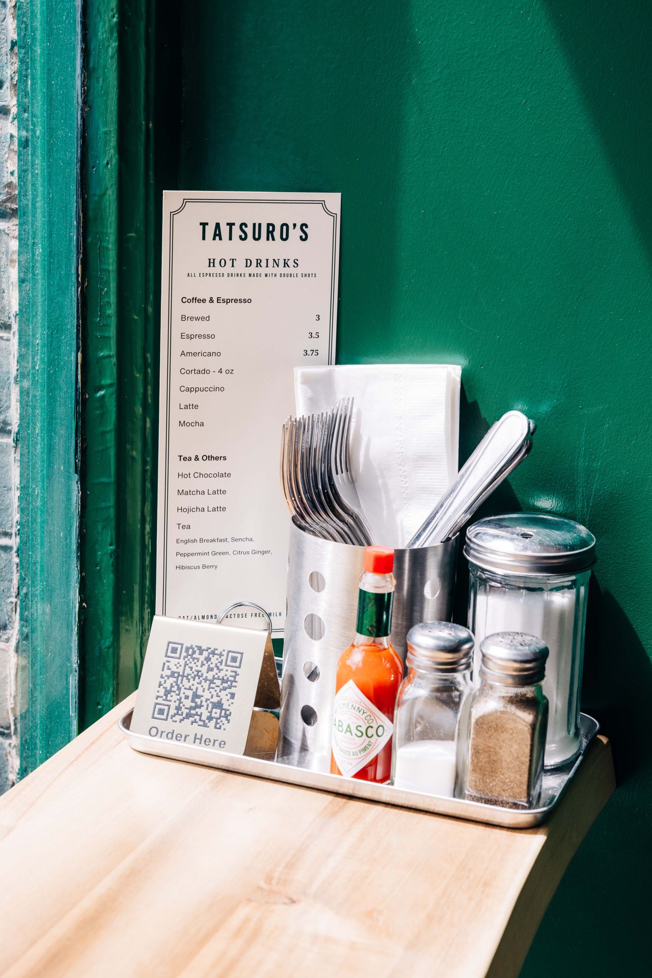 A tray of condiments, cutlery and a menu on a table at a restaurant
