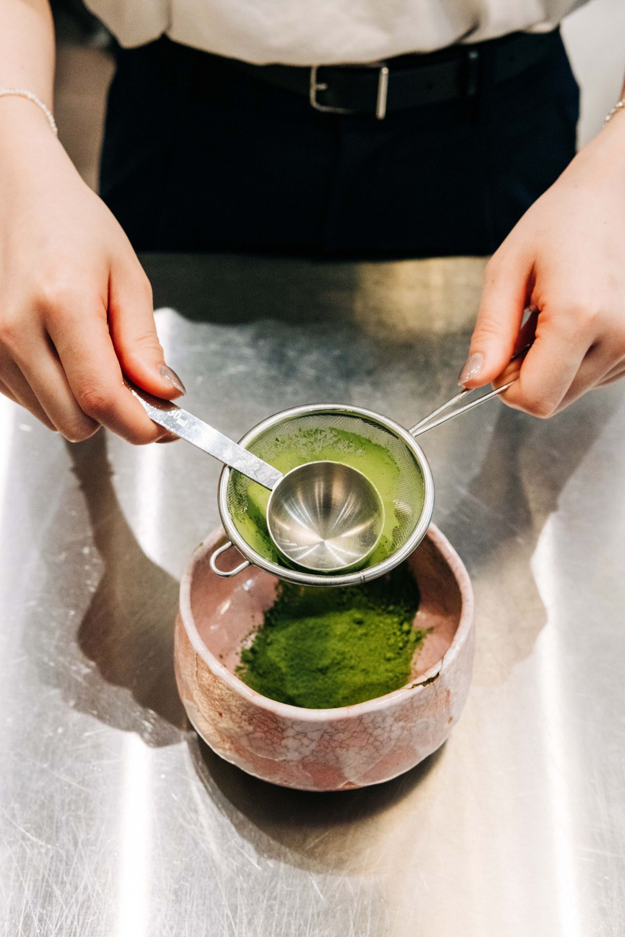 A person puts matcha through a sieve