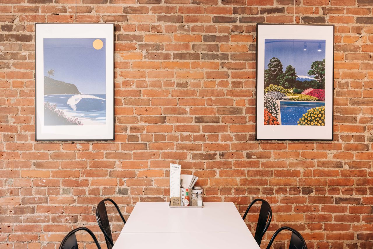 Art hangs on exposed brick walls in the dining room of Tatsuro's