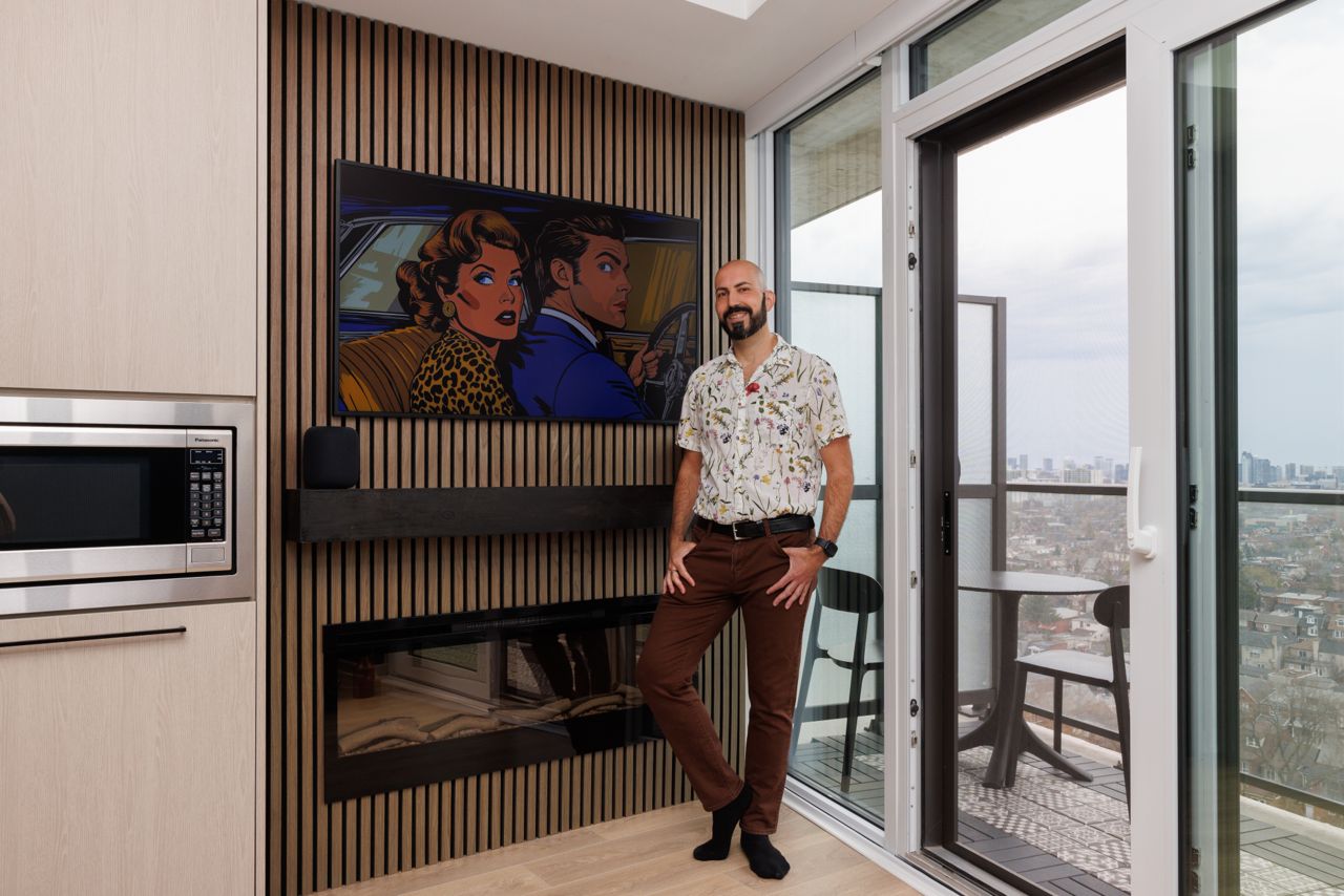 Charles poses in front of his fireplace in his condo.
