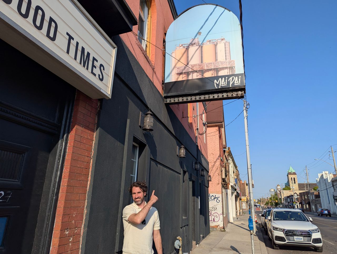 Chef Eric Robertson stands outside Maipai, a pizzeria in Hamilton, and points at the restaurant's sign