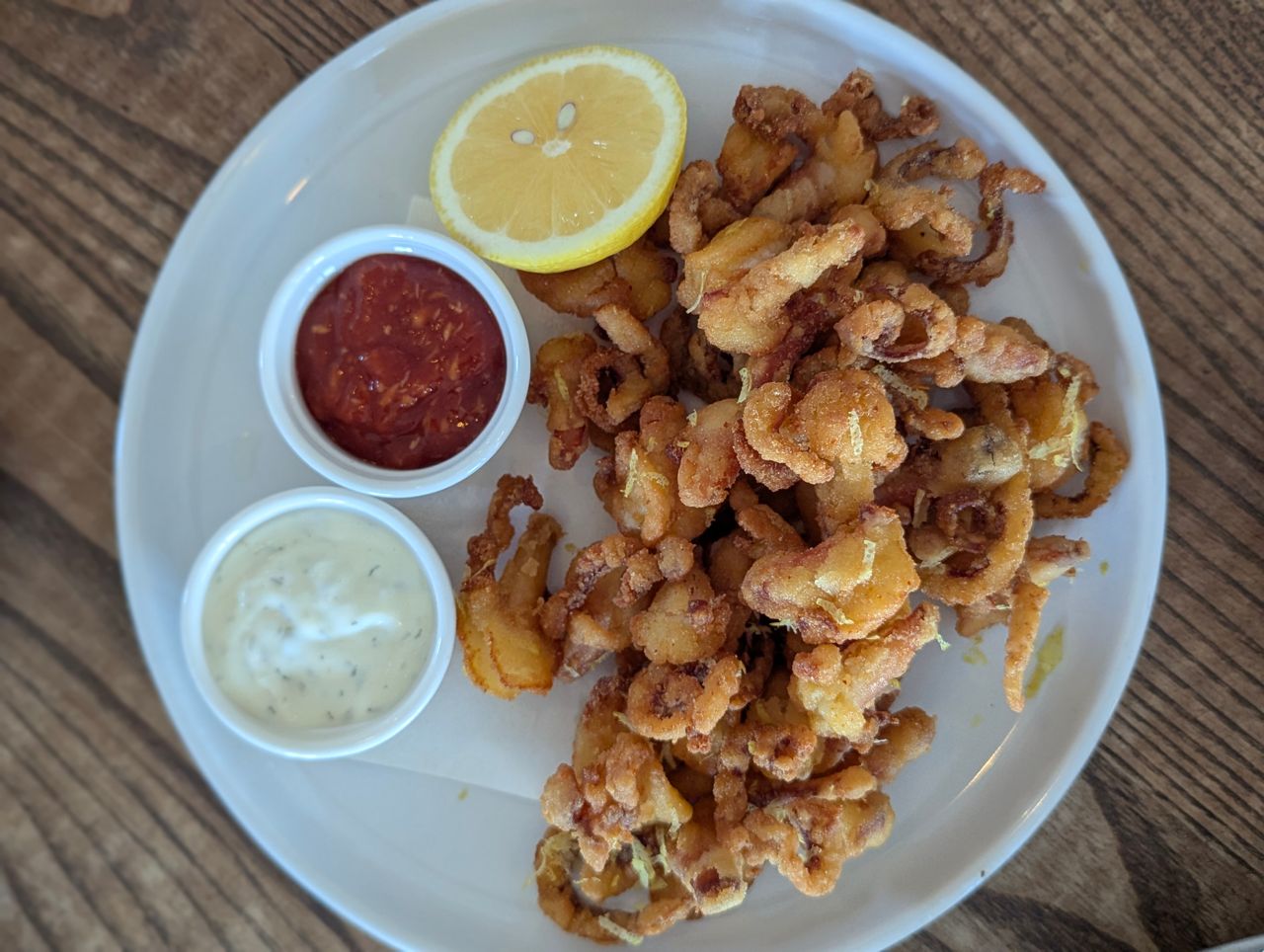 A plate of deep-fried clams with lemon and sauces