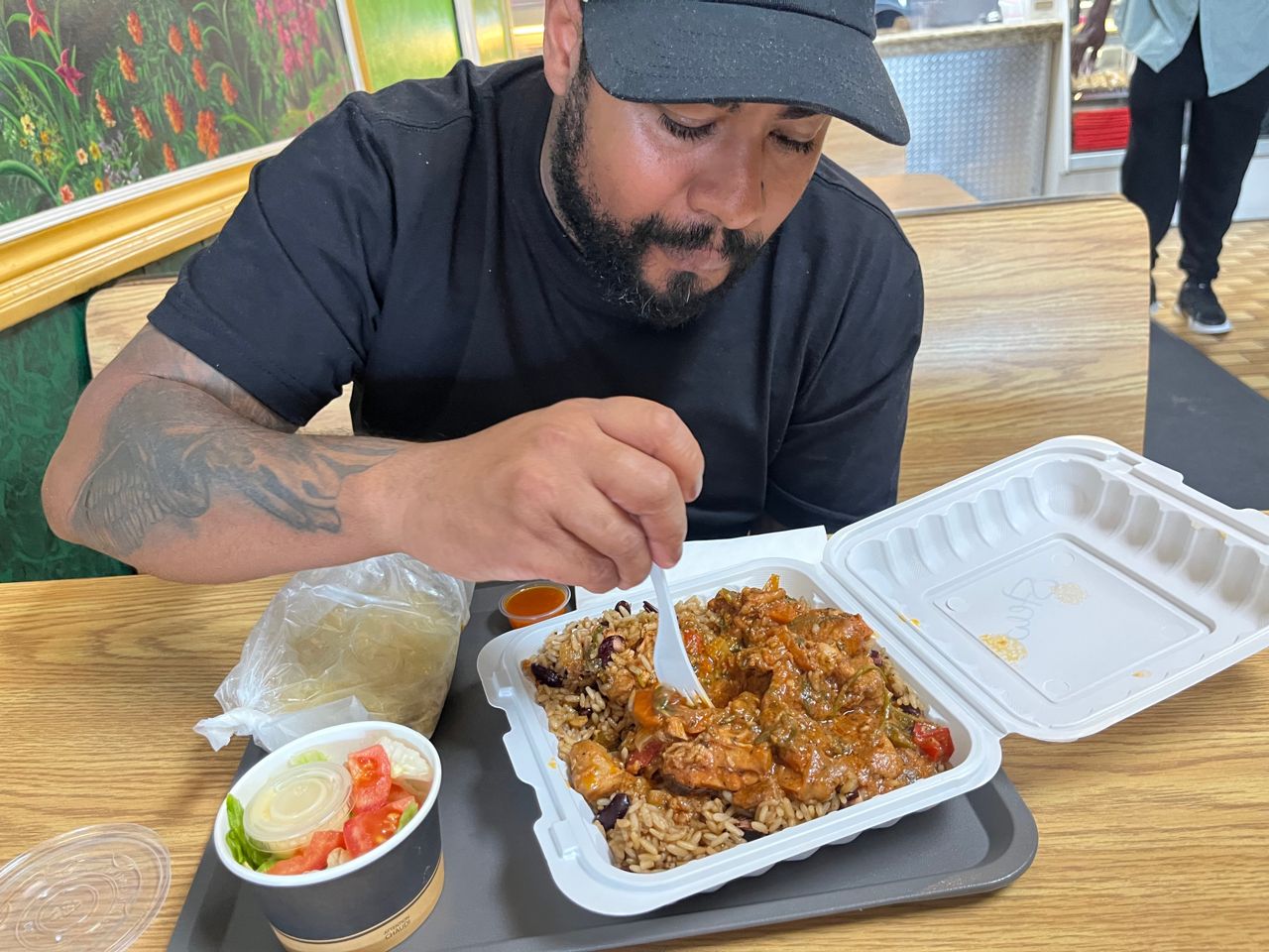 Chef Jerome Robinson digs into a takeout container filled with stewed chicken and rice