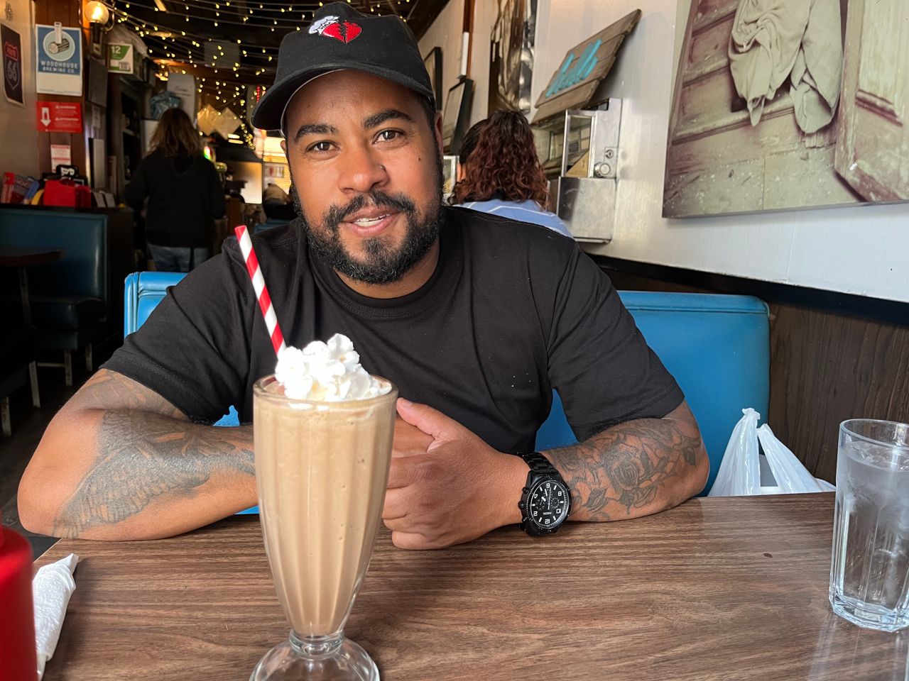 Chef Jerome Robinson sits in a booth at a diner with a chocolate milkshake