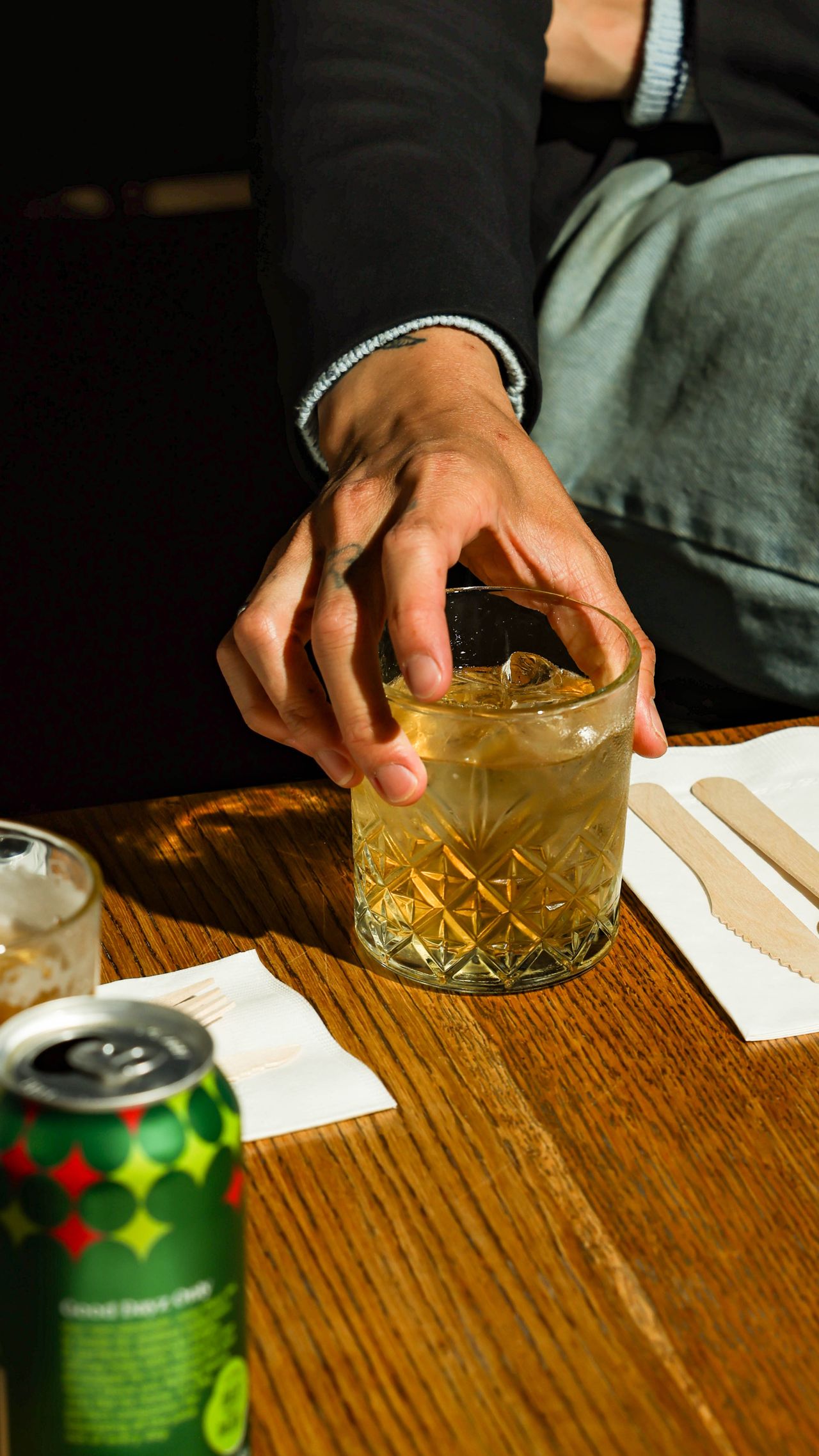 A person picks up a drink in an old-fashioned glass
