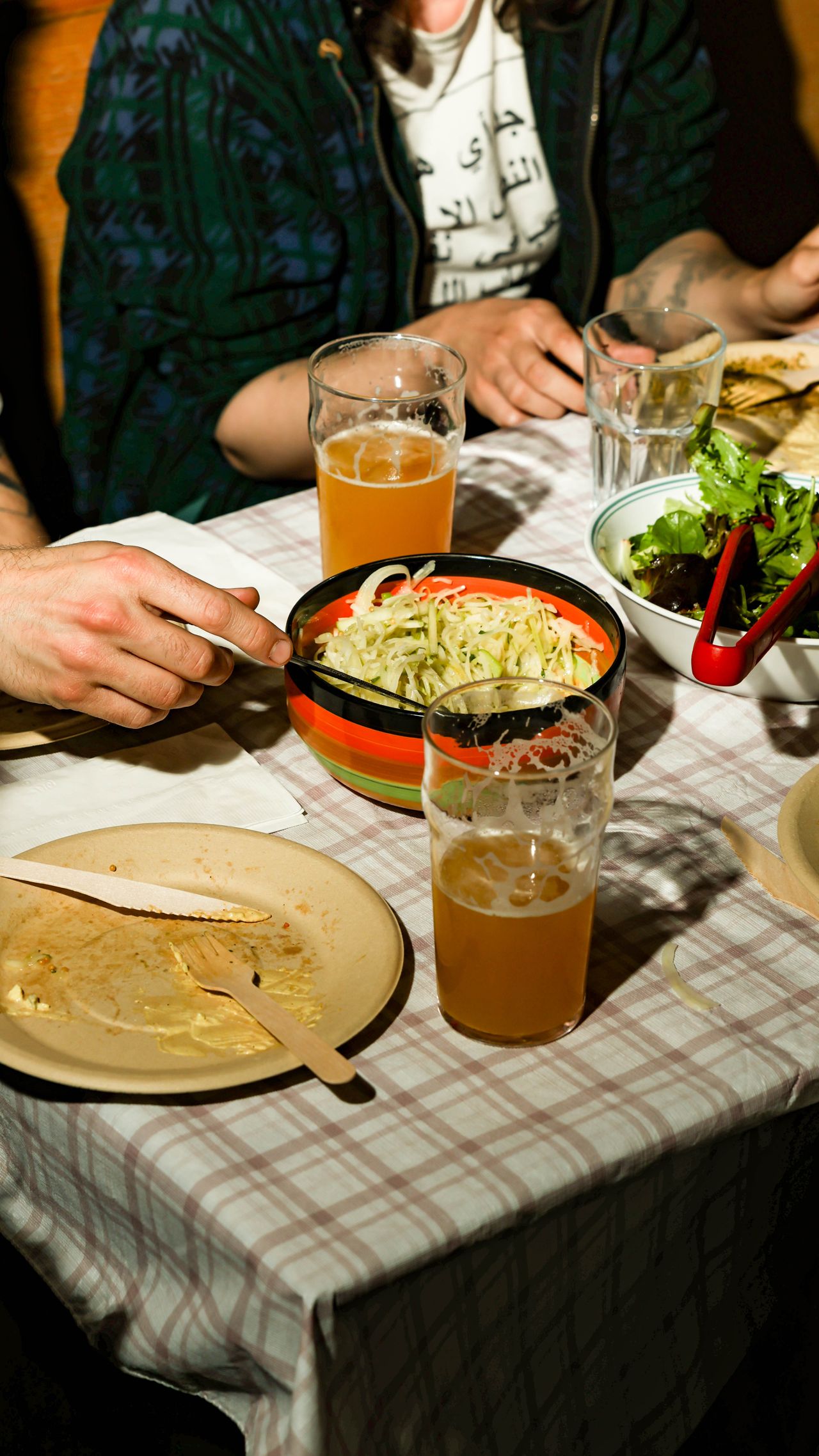 People sit at a table set with salads and pints of half-finished beer