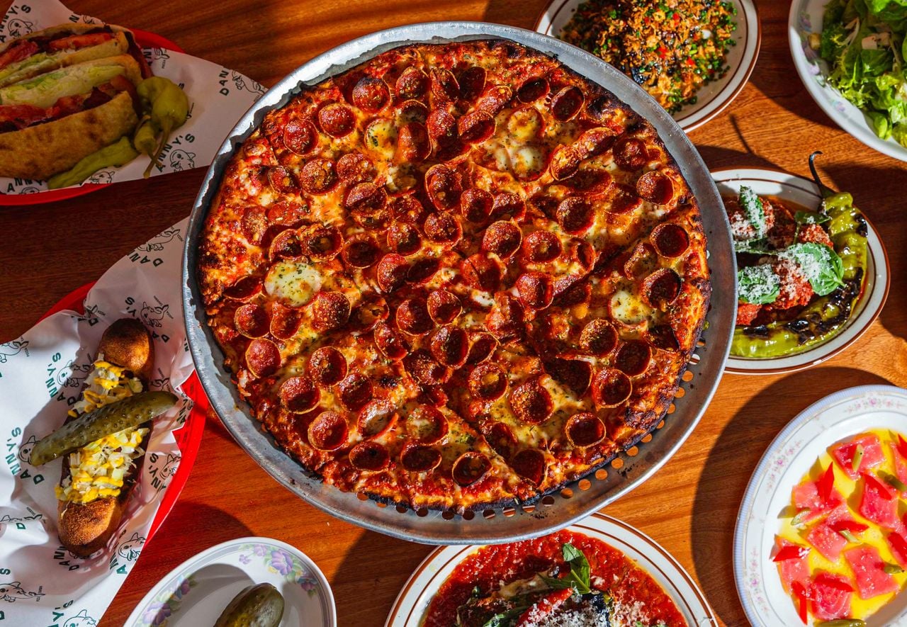 A pepperoni pizza surrounded by side dishes