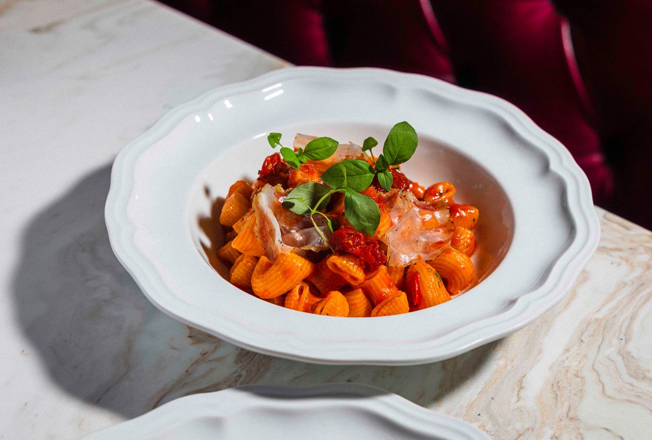 A bowl of lumaconi with tomato, Thai chilies and guanciale