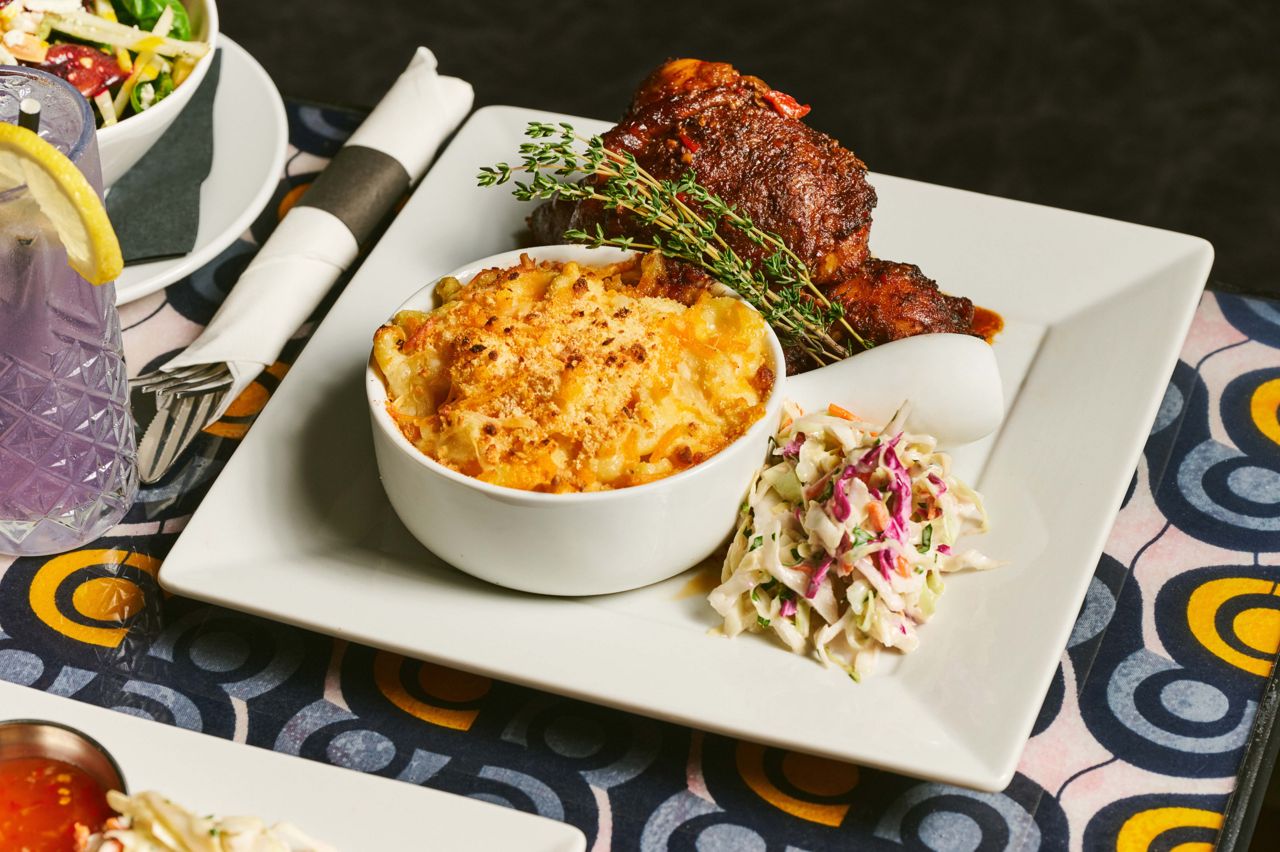 Smoked over applewood in a traditional jerk pan and finished with a miso-chili glaze, the ultra-juicy jerk chicken is served with mac and cheese and crisp cabbage slaw