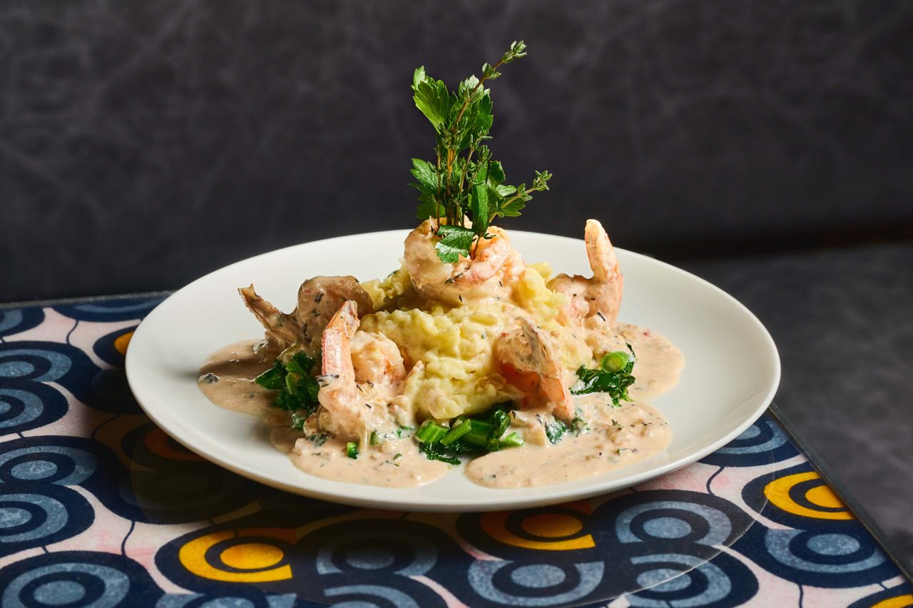 Shrimp are simmered in coconut milk and scotch bonnet pepper, and served over mashed potato with sweet corn