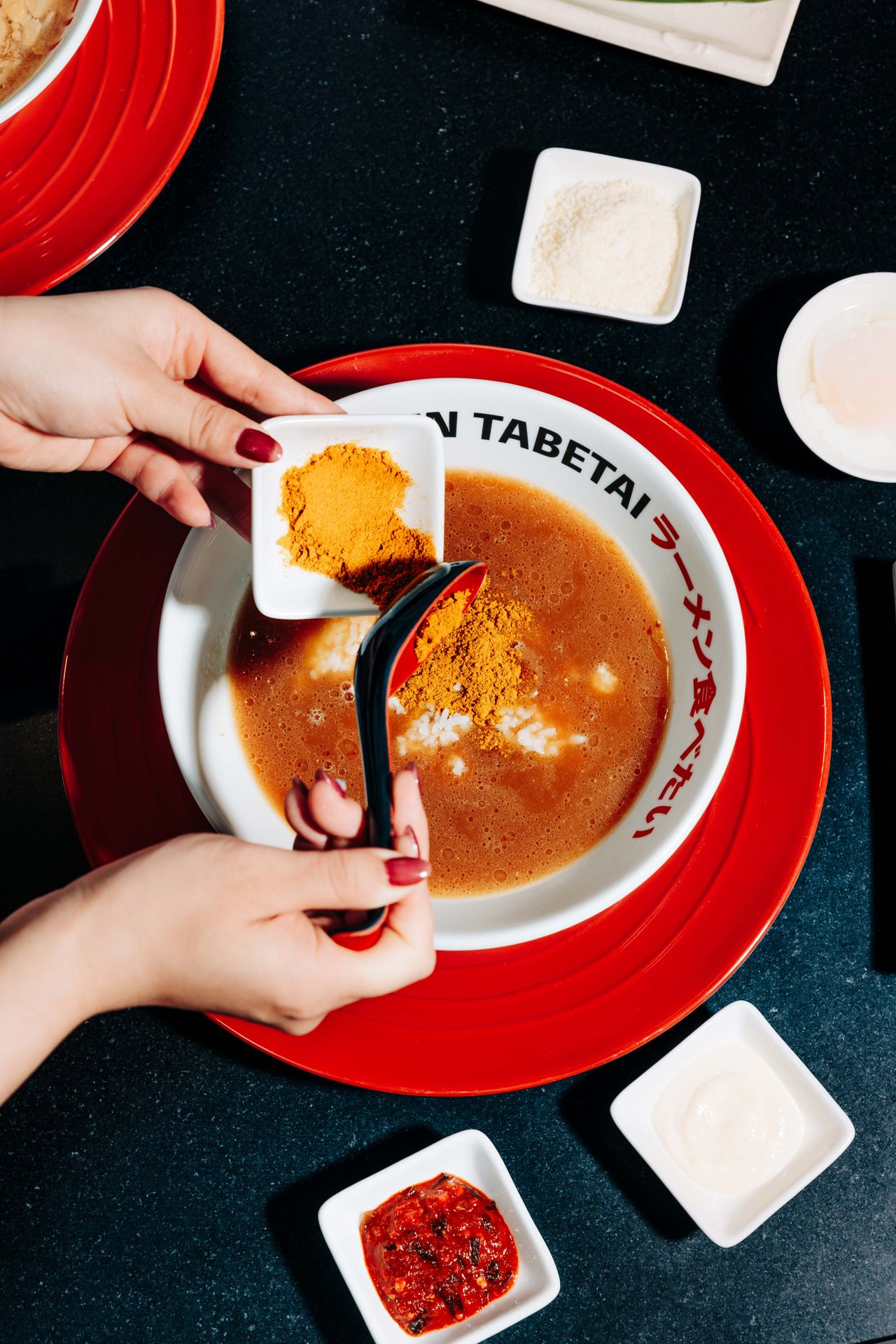 A person adds Japanese curry powder into a bowl of broth with rice