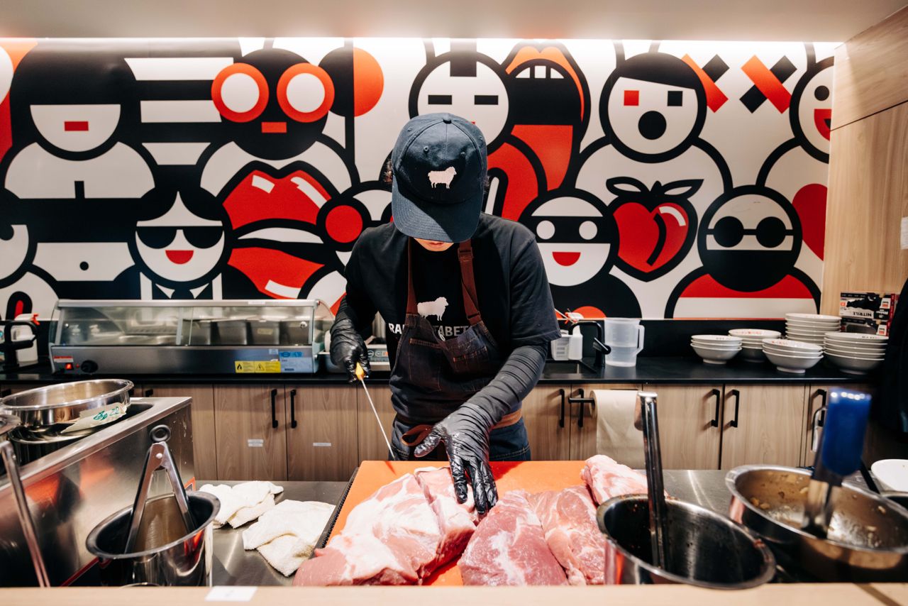 A chef at Ramen Tabetai in Toronto slices pork