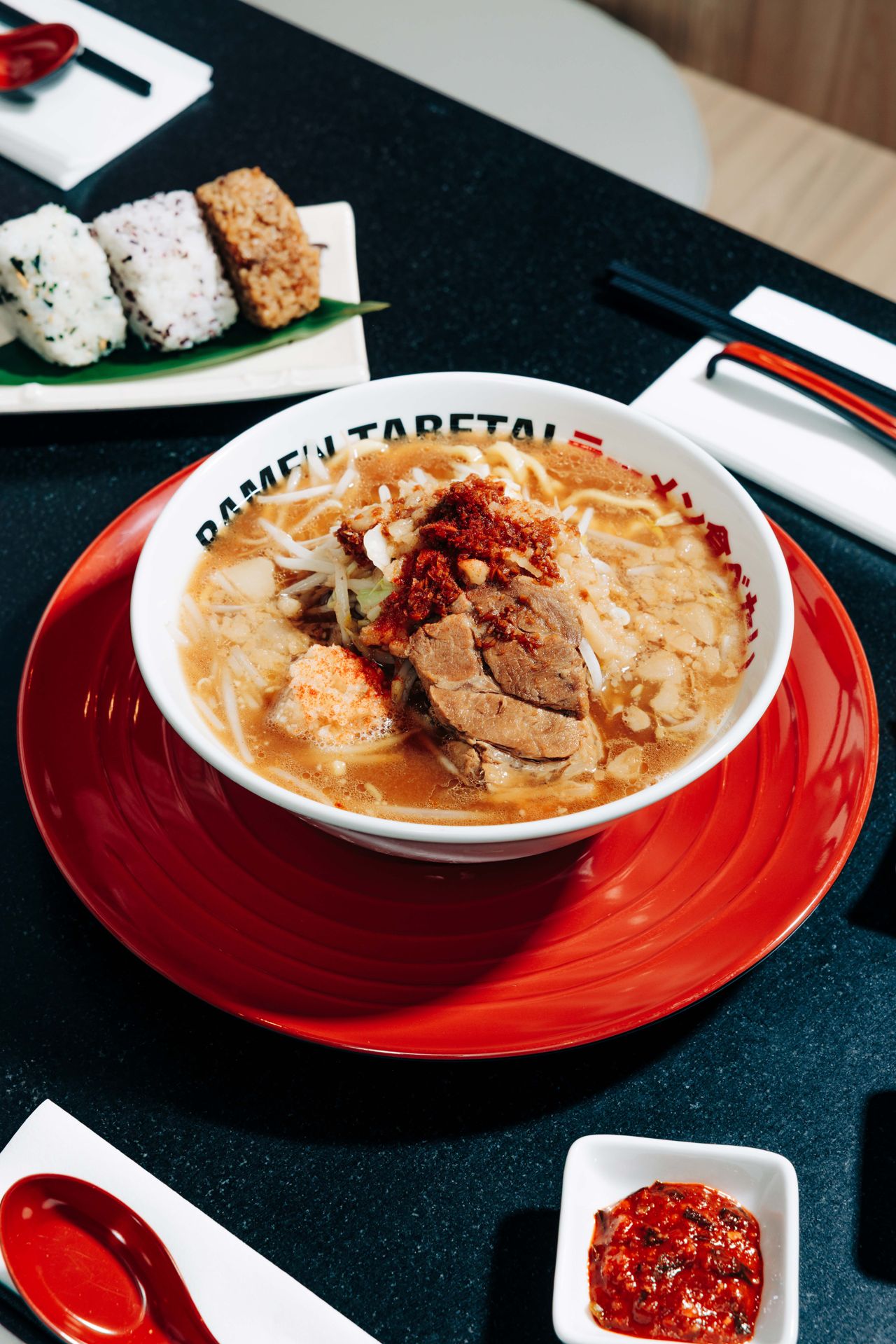 A bowl of tonkotsu ramen next to some onigiri
