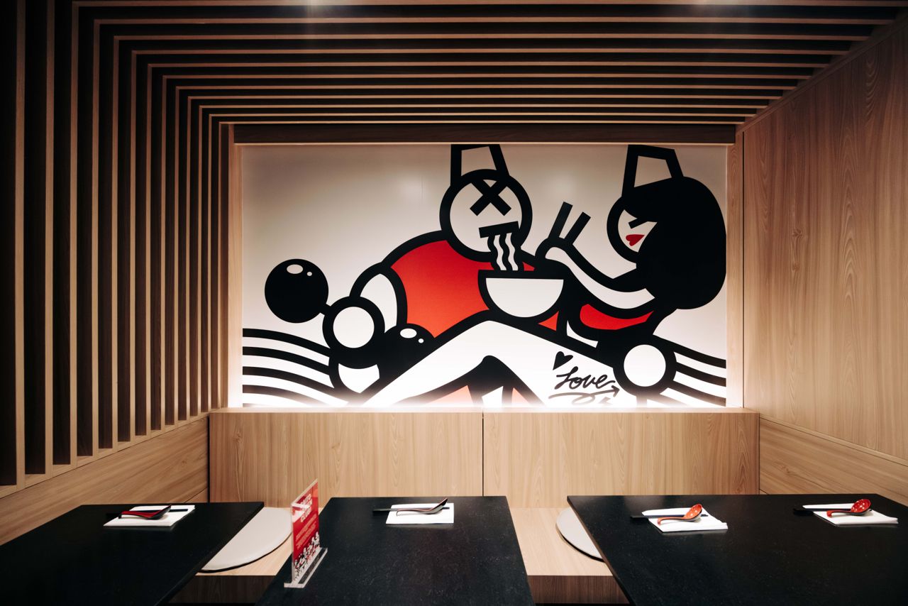 A mural of two people eating ramen decorates one wall at Ramen Tabetai