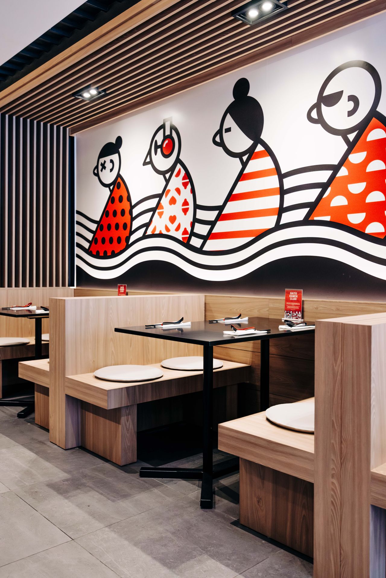 Booth seating in front of a mural at Ramen Tabetai in Toronto