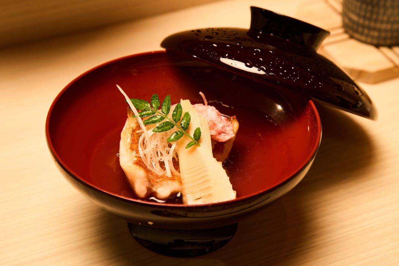 The kichiji soup features the catch of the day, grilled and bathing in an aromatic bonito broth, along with bamboo shoots, a fried sakura flower, shredded scallions and a sansho leaf