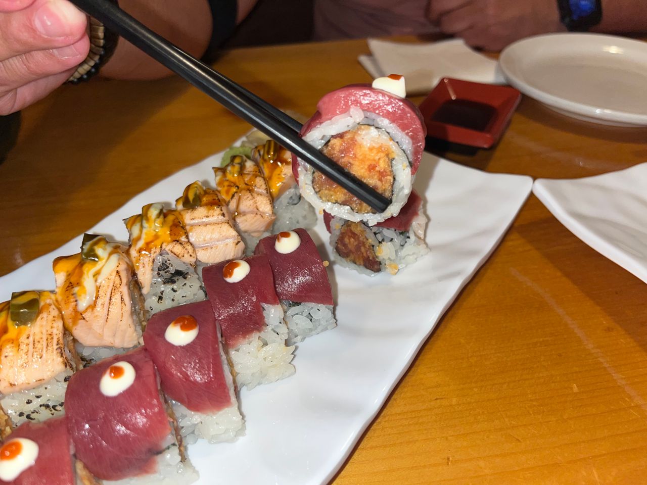 A person uses chopsticks to hold a spicy salmon roll