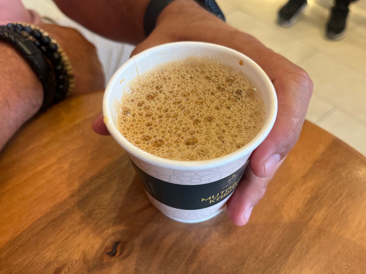 A person holds a paper cup of chai