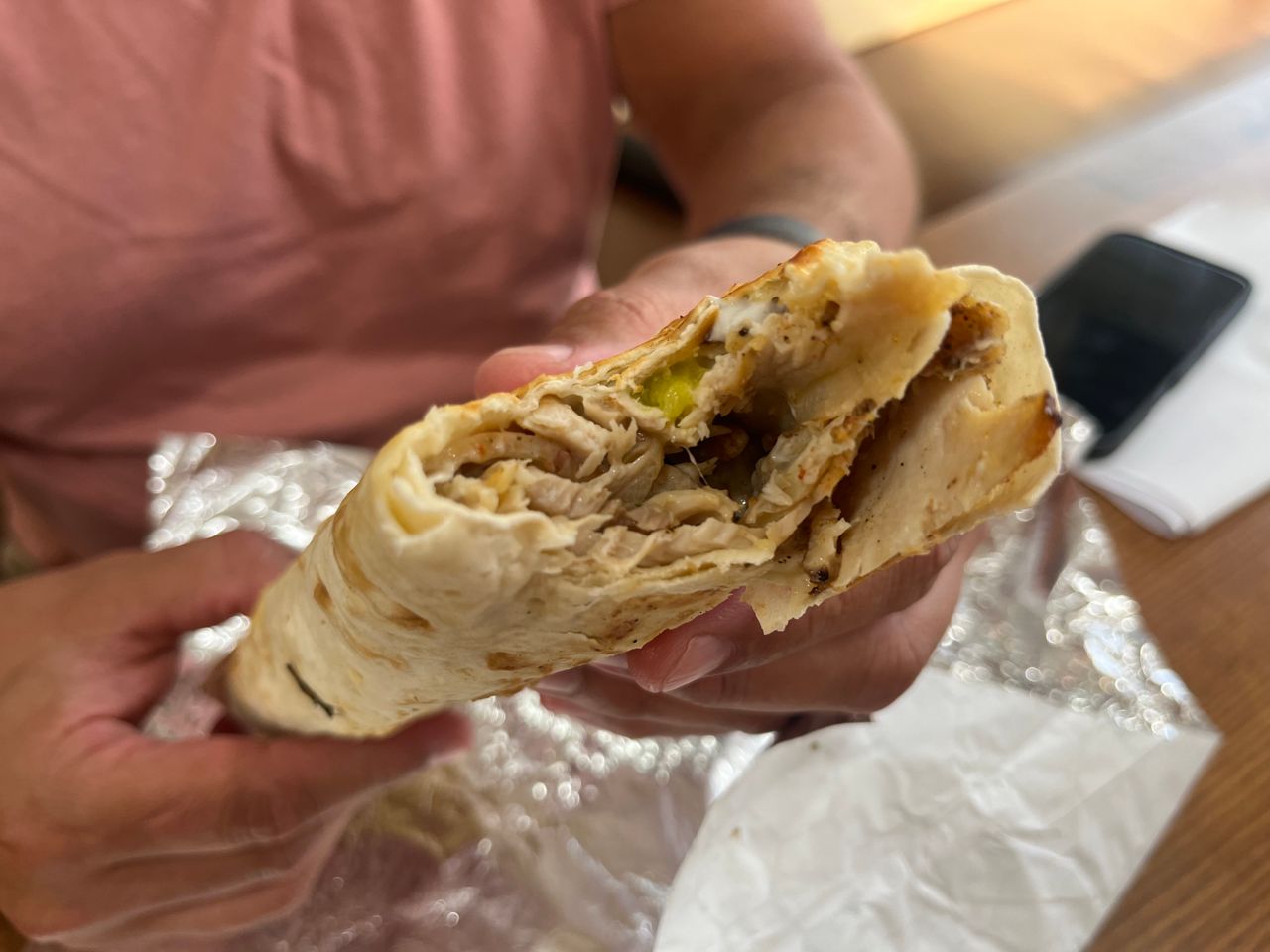 A closeup of a chicken shawarma wrap with a bite taken out of it