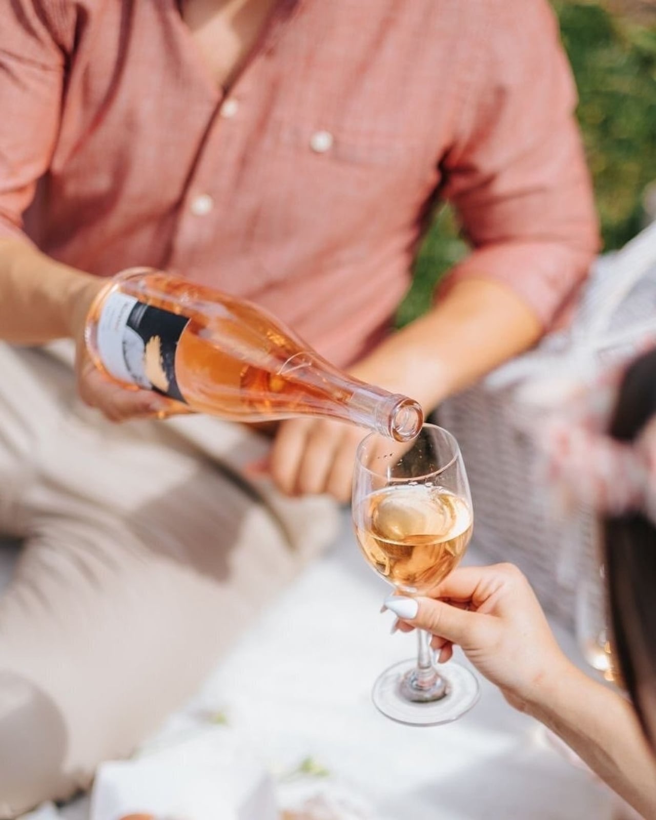 A person pours rose from a bottle into a glass