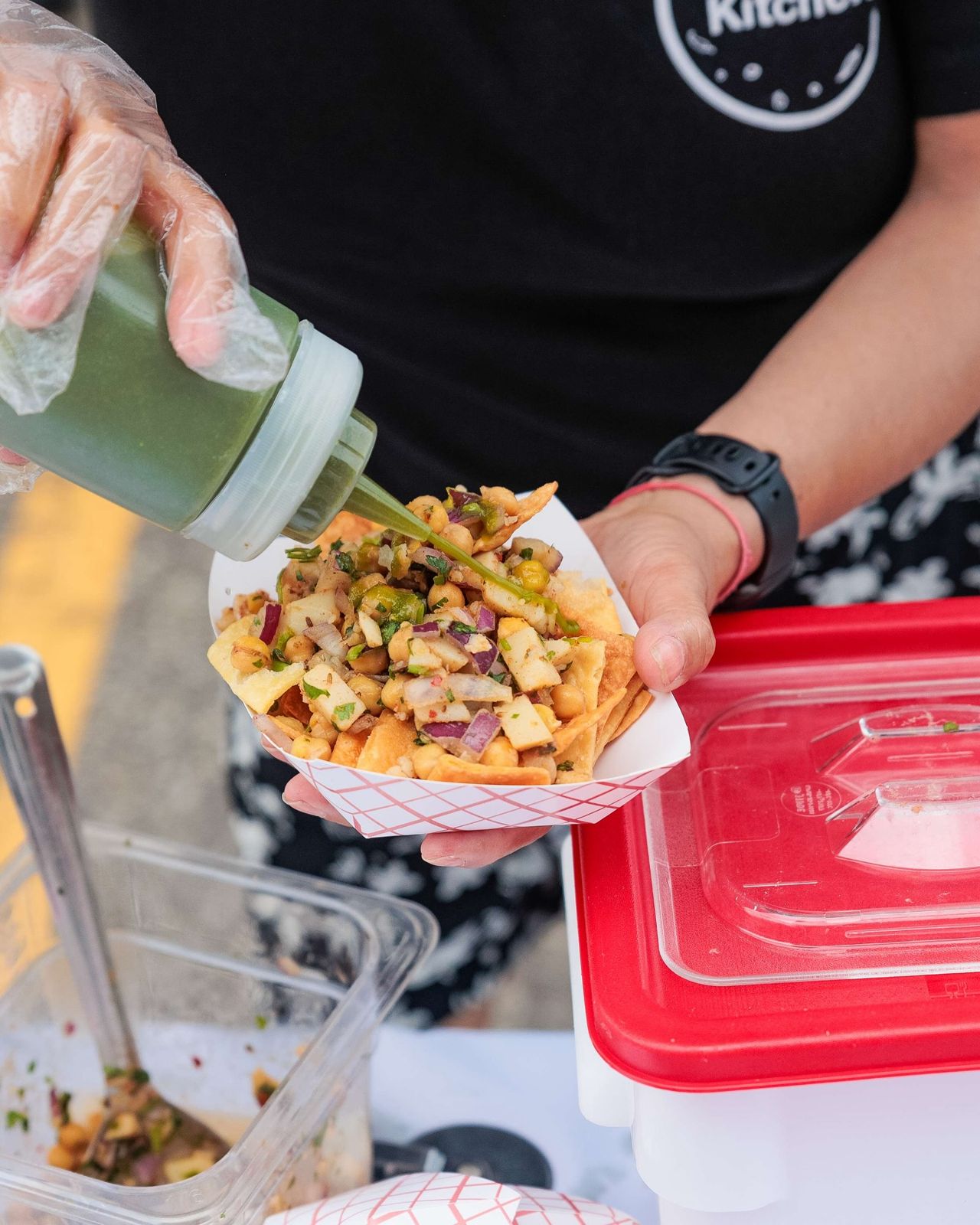 A person squirts sauce onto a dish at a food festival