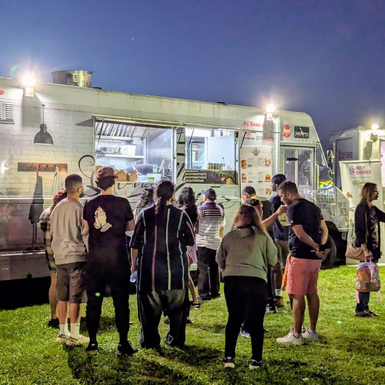 People line up at a food truck in a park