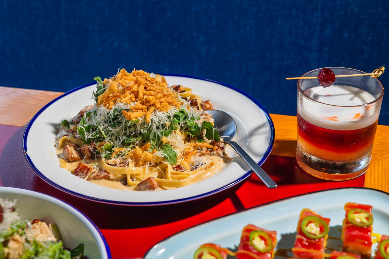 A bowl of pasta next to a cocktail