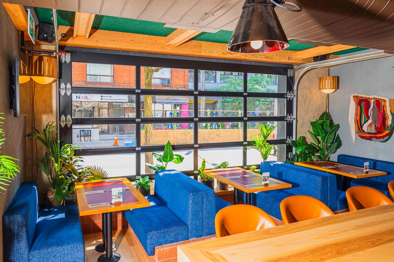 Booth seating next to a roll-up garage window at Central, a bar and restaurant in Toronto