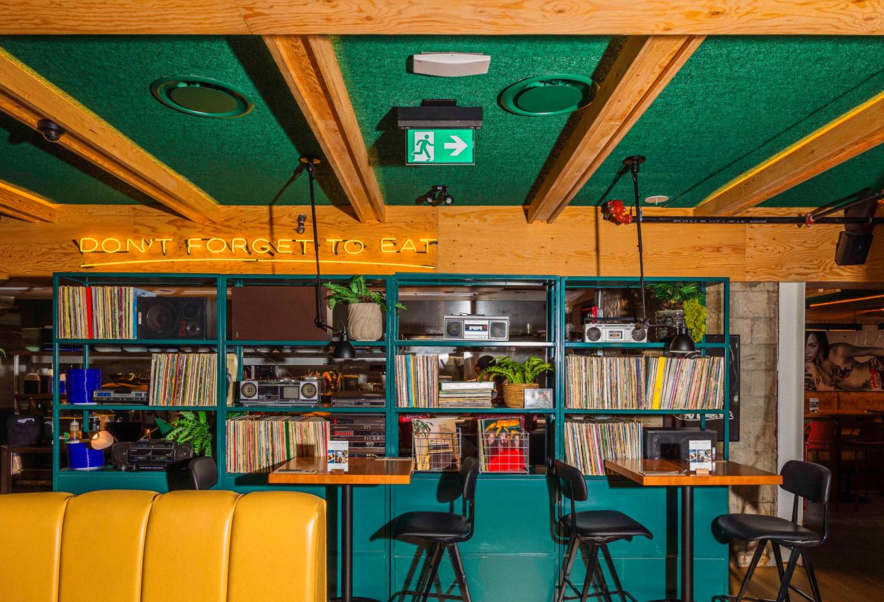 Two-top tables next to shelves stocked with records and old radios
