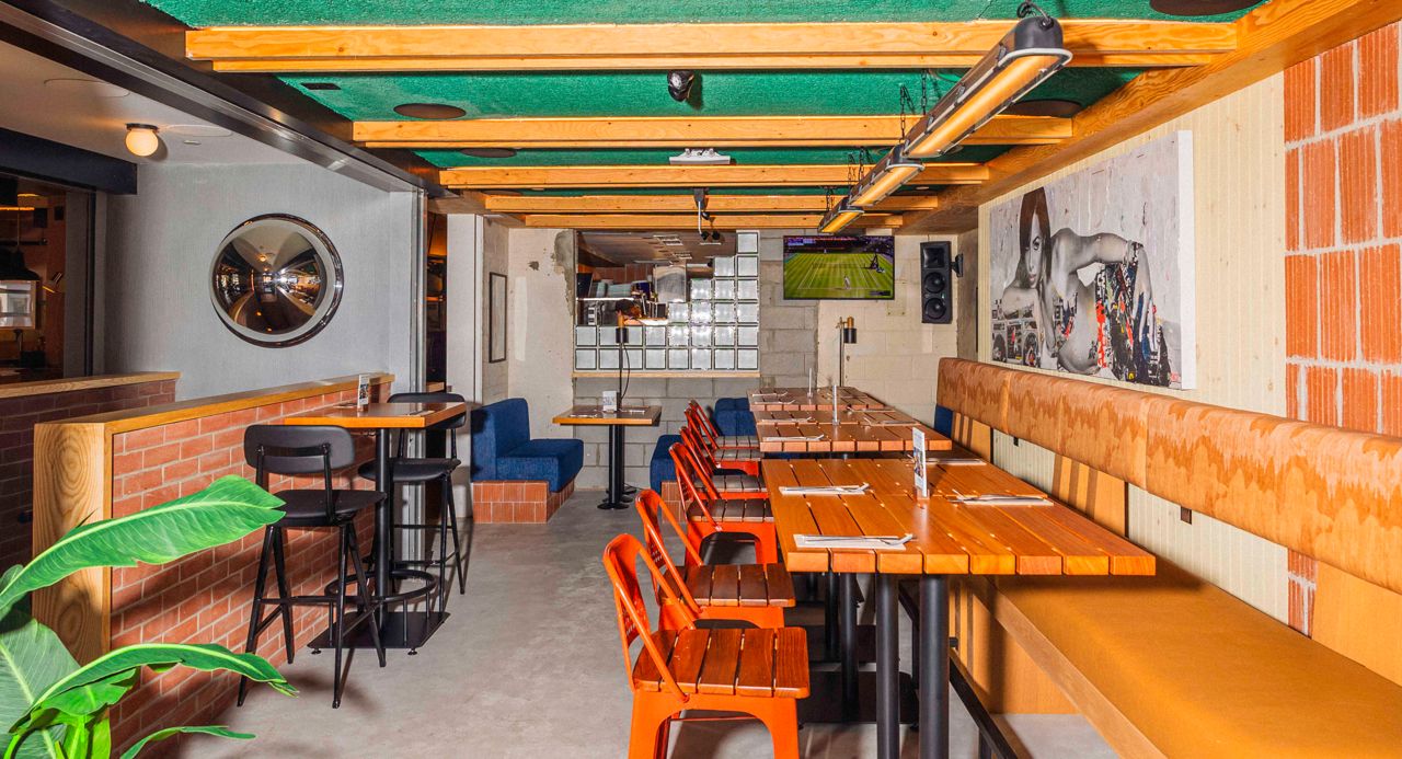 Banquette seating and two-top tables in a dining room next to the main one at Central, a bar in Toronto