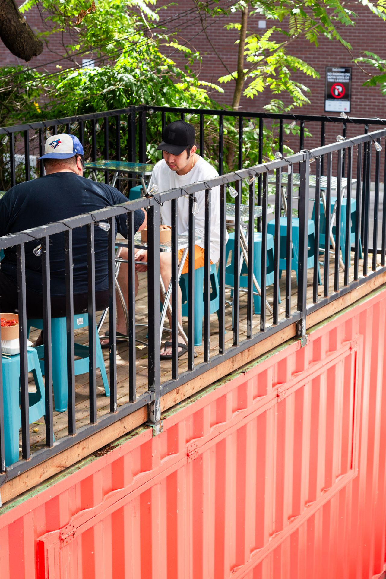 People eat on the patio of a shipping container restaurant in Toronto
