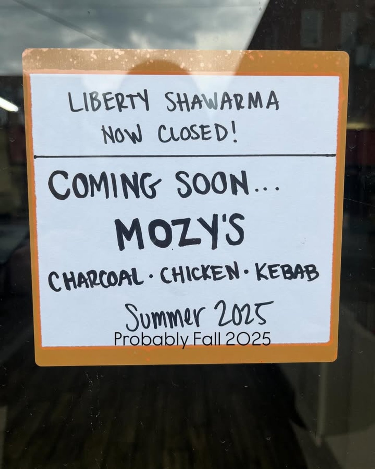 A sign on a door announces the opening of Mozy's Charcoal, a kebab shop in Toronto's Liberty Village neighbourhood
