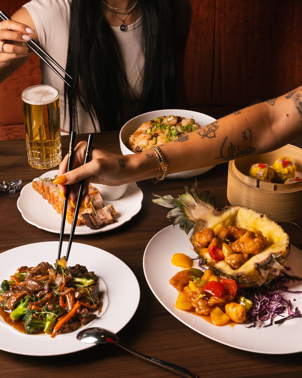 People use chopsticks to eat a spread of Chinese dishes