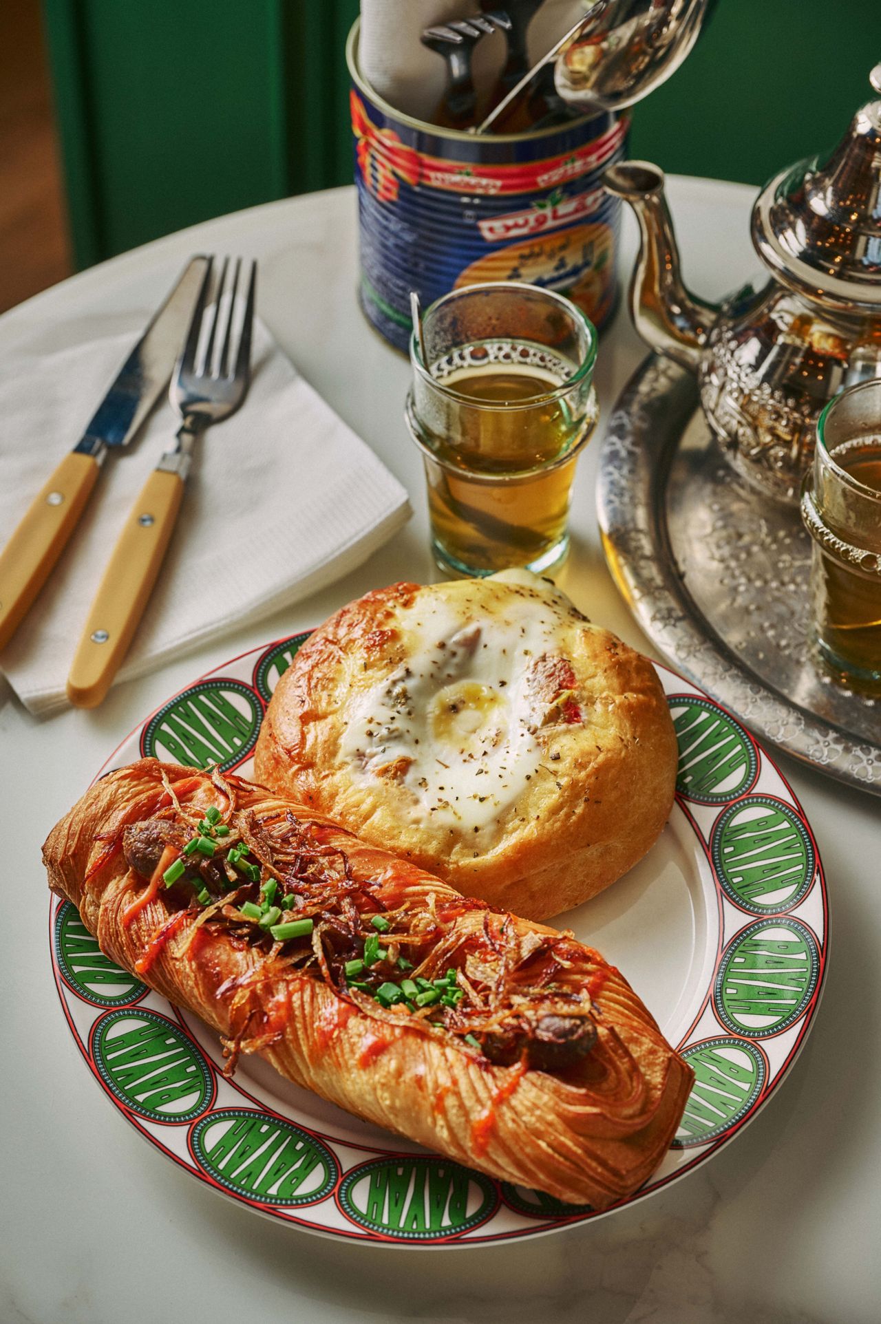A soft brioche bun filled with roasted peppers, topped with a cracked egg and oregano; and a croissant stuffed with house-made merguez sausage, harissa aïoli, fried shallots and chives