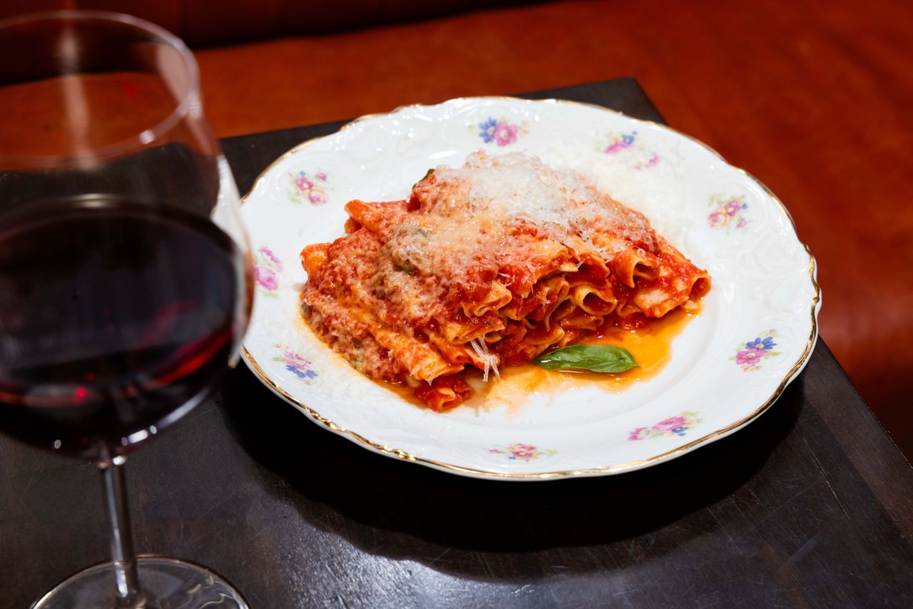 A plate of ziti with a glass of red wine
