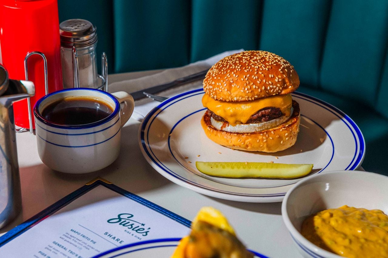 A cheeseburger served with a pickle spear