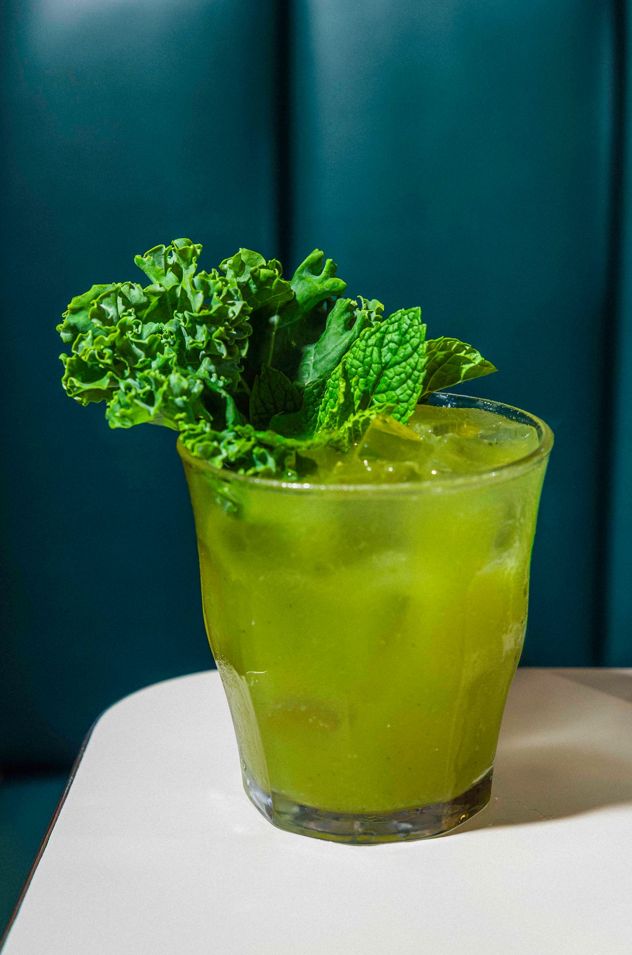 A glass of green juice garnished with kale