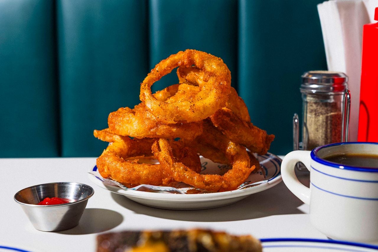 A plate of onion rings next to a mug of coffee