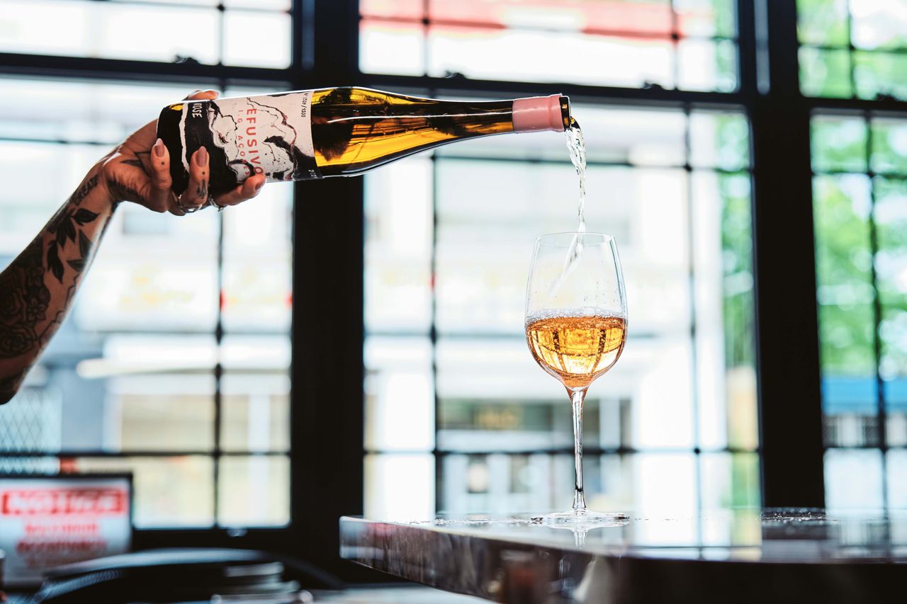 A person pours wine from a bottle into a glass
