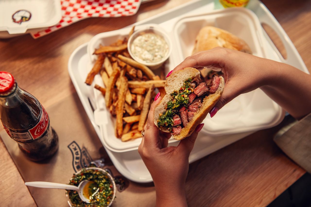 A person holds a sandwich from Bear Steak Sandwiches